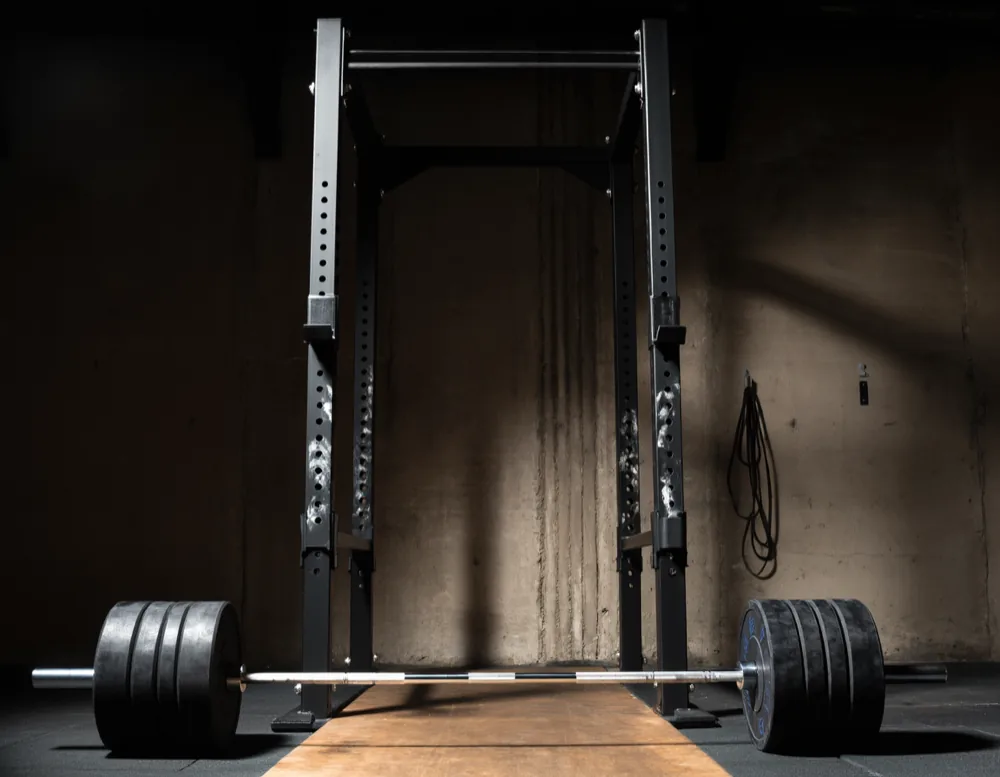 Steel power rack with a loaded bar racked at squat height, chalk handprints on the upright